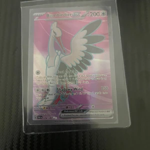 Bombirdier ex Pokémonkort - Säljer ett holografiskt Bombirdier ex Pokémonkort med 200 HP. Kortet har attacker som Fast Carrier och Shadowy Wind. Det är i en skyddande plastficka och har en färgglad, skimrande yta.