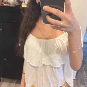 Vit offshoulder blus - Säljer en söt vit offshoulder blus med volangdetaljer. Perfekt för sommardagar och ger en luftig och stilren look. Blusen har en avslappnad passform och är tillverkad i ett lätt material.