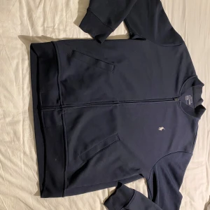 Mörkblå hoodie från Polo Ralph Lauren - Säljer en stilren mörkblå hoodie från Polo Ralph Lauren. Tröjan har en dragkedja framtill och det ikoniska broderade logotypen på bröstet. Perfekt för en avslappnad look. 🐎