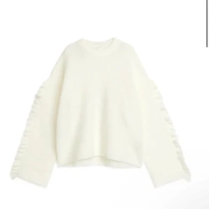 Vit stickad tröja med volanger - Vit stickad tröja i alpacka ull. Volanger längst ärmarna. Storlek M men sitter e utmärkt på mig (165) om man är ute efter en oversized passform. Aldrig tvättad och därav nyskick🩷🩷🩷