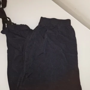 Svarta byxor med snörning - Säljer ett par svarta byxor med snörning i midjan och vid benen.  Perfekta för en avslappnad stil och bekväma att bära. Byxorna har en loose passform och är tillverkade i ett mjukt material.