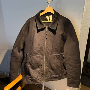 Svart jacka med dragkedja ARKET - Snygg mörkblå jacka med dragkedja och två stora fickor framtill. Jackan har en klassisk krage och är långärmad, perfekt för kyligare dagar. Enkel och stilren design som passar till det mesta.