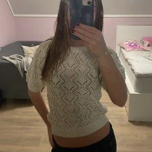 Vit stickad topp - Säljer en söt beige stickad topp med korta ärmar och ett fint hålmönster. Den har en liten fläck men den syns inte så tydligt(de sista bilden).
