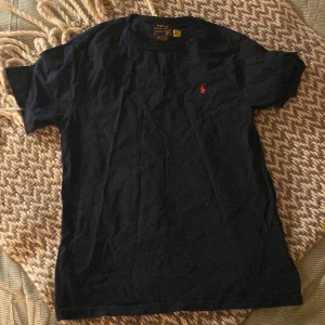 Mörkblå t-shirt från Ralph Lauren - Snygg mörkblå t-shirt från Ralph Lauren. Kommer tyvärr inte till användning och är heller knappt använd. Inga defekter och inga fläckar. Den är storlek 14-16 år gammal 💕 hör av er vid frågor eller om ni vill ha fler bilder! Priser kan diskuteras!