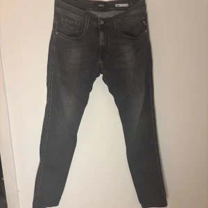Grå Replay Anbass jeans - Snygga grå Replay Anbass jeans i slim fit. De har en klassisk femficksdesign med dragkedja och knapp. Perfekta för en stilren look med en modern touch. Bra skick inga defekter w33 L34 passar 175-185cm skulle ja säga
