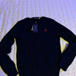 Mörkblå stickad tröja från Polo Ralph Lauren - Helt oanvänd,  Mycket bra kvalité och lapparna är kvar. mycket varm och är perfekt för lite kyligare väder. Ett perfekt plagg för din garderob 