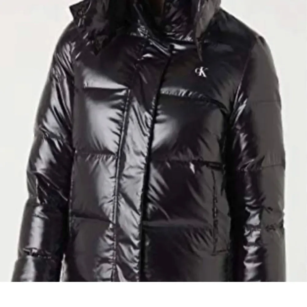 Snygg svart glansig dunjacka från Calvin Klein med huva och dragkedja. Jackan har en pufferdesign och CK-logga på bröstet. Köptes innan vintern nypris-ca 2100 beroende på sida. Storlek S. Takit.