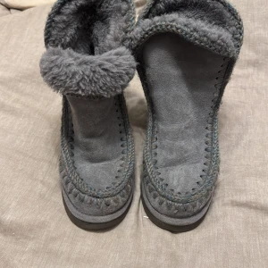 Grå boots från Mou - Säljer ett par grå boots från Mou i grå mocka med mjukt foder. Skorna har en unik stickad detalj runt kanterna och en robust sula. Perfekta för kyligare dagar. Storlek står inte men upplever det som 38.