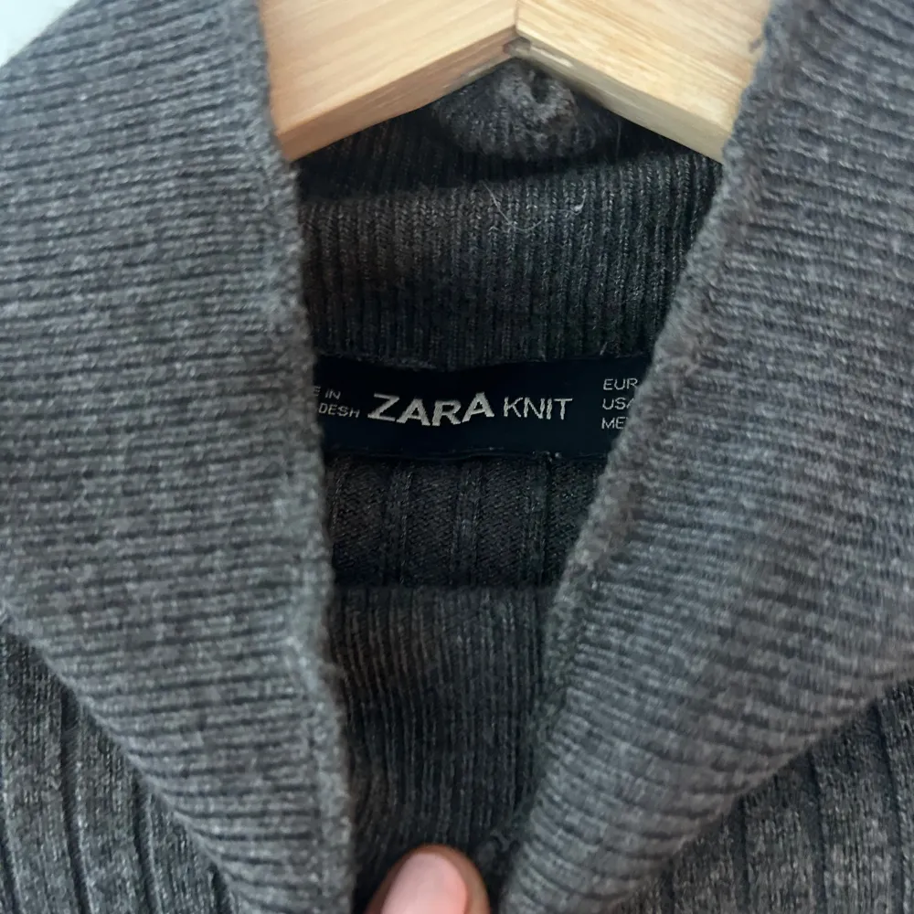 Säljer en stilren grå ribbad polotröja från Zara. Tröjan har en tight passform och långa ärmar, perfekt för kyligare dagar. Den är tillverkad i ett mjukt material som ger en bekväm känsla. Passar utmärkt till både jeans och kjol.. Neuletakit & Villapaidat.