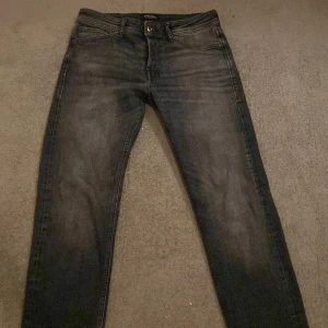 Svarta jeans från Jack & Jones - Snygga svarta jeans från Jack & Jones med en klassisk femficksdesign. De har en knappgylf och är perfekta för en stilren look. Passar bra till både vardag och mer uppklädda tillfällen.