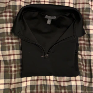 Svart långärmad halv zip - Säljer en stilren svart långärmad halv zip tröja från H&M. Tröjan har en praktisk dragkedja vid halsen och är perfekt för en avslappnad look. Passar bra till både jeans och träningsbyxor.