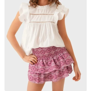 Rosa volangkjol meet me there - Säljer en rosa kortkjol med ett färgglatt mönster. Kjolen har volangdetaljer som ger en fin look. Perfekt för varma dagar! 