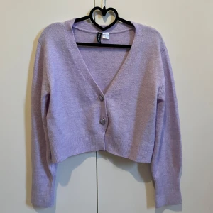 Ljuslila kofta från H&M Divided - Säljer en söt ljuslila kofta från H&M Divided. Den är croppad med långa ärmar och har hjärtformade knappar framtill. Perfekt för en mysig dag eller en stilren look. Skriv för fler bilder eller funderingar💕