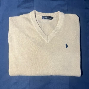 Beige Ralph Lauren V-neck tröja - Säljer en V-neck tjocktröja från Ralph Lauren!  Färg 🎨📊 Tröjan har en ”cream” färg då den är lite ljusbrun aktig  Mått📏 Längd : 70 cm Lång 50 cm Bred Storlek M  Skick☘️ Tröjan är i perfekt skick utan defekter eller hål!  Material🧵 80% cotton (se sista bilderna)