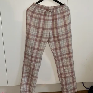 Pyjamasbyxa från La Redoute - Säljer ett par bekväma pyjamas byxor från La Redoute. Byxorna har en elastisk midja med en rosett där fram och ett klassiskt rutmönster i rosa och beigea toner med glitter detaljer. Säljer då dom är för små.