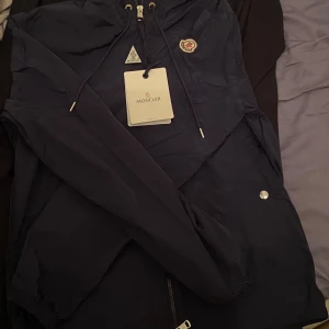 Mörkblå vindjacka från Moncler - Säljer en snygg mörkblå vindjacka från Moncler med huva och dragkedja. Jackan har en fungerande scan. 
