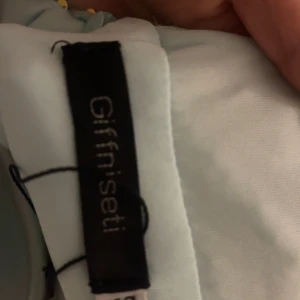 Glittrig blå klänning från Giffnseti - Säljer en fantastisk glittrig blå klänning från Giffnseti. Klänningen har en v-ringad design och är täckt med paljetter som ger en magisk look. Perfekt för speciella tillfällen där du vill glänsa! Aldrig använd 