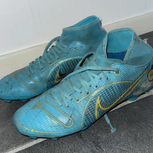 Blå/gula Nike mercurials  - Jag säljer dessa blåa Nike mercurials som jag har använt för ca 4 år sen dem är slitna där i bak lite. Dem  har ett litet hål men dem går fortfarande och använda annars är det inget fel med dem än att va smutsiga men såklart kan jag fixa det innan jag skickar ut.