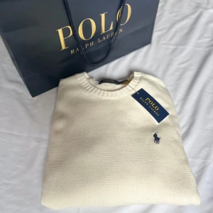 Vit tröja från Ralph Lauren - Säljer en stilren vit tröja från Ralph Lauren med det klassiska logotypbroderiet på bröstet. Tröjan har en rund halsringning och är perfekt för en elegant och avslappnad look. Passar bra till både jeans och chinos. Helt ny, kvitto ingår (2399 kr i butik.) Perfekt till våren. Bara att höra av sig vid frågor//Carl.