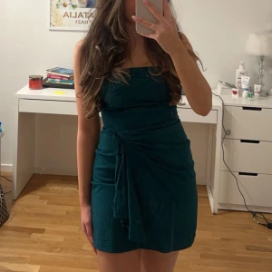 Mörkgrön axelbandslös klänning - Snygg mörkgrön axelbandslös klänning. Perfekt för en kväll ute eller en speciell tillställning. Klänningen har en kort längd och en elegant passform. Väldigt liten i storleken, passar en liten xs. Använd fåtal gånger. 