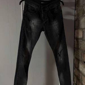 Svarta jeans från Dsquared2 - KOM MED BUD!!!! Snygga svarta jeans från Dsquared2 med slitna detaljer och en cool tvätt. De har en klassisk femficksdesign och en diskret logotyp på bakfickan. Perfekta för en trendig look. Använt byxorna 1-3 gånger bara men det har bara varit när jag testat dom och sånt.