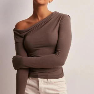 Brun oneshoulder topp - Snygg brun oneshoulder topp med lång ärm från Nelly. 