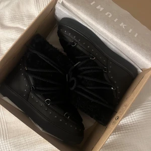 Svarta boots från Inuikii - Snygga svarta boots från Inuikii med snörning och pälsdetaljer. (Curly rock modellen). Helt nya aldrig använda. Köpte för stora. Ny pris 3700