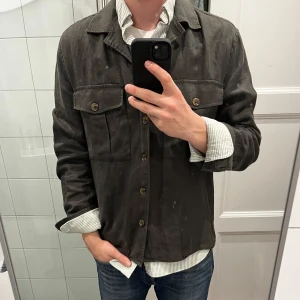Mörkgrön overshirt - Säljer en stilren mörkgrön overshirt med knappar framtill. Jackan har två bröstfickor med knappar, vilket ger en schysst och avslappnad look. Perfekt för lager-på-lager-stil till våren. 