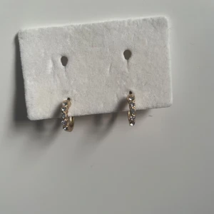 Guldörhängen med stenar - Snygga guldörhängen med glittrande stenar. Perfekta för att ge en touch av elegans till din stil. De är små och diskreta men ändå iögonfallande.