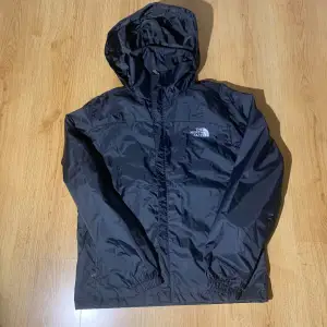 Säljer en svart vindjacka från The North Face med huva och dragkedja.                                           Storlek L men skulle säga att den passar M skriv för frågor 