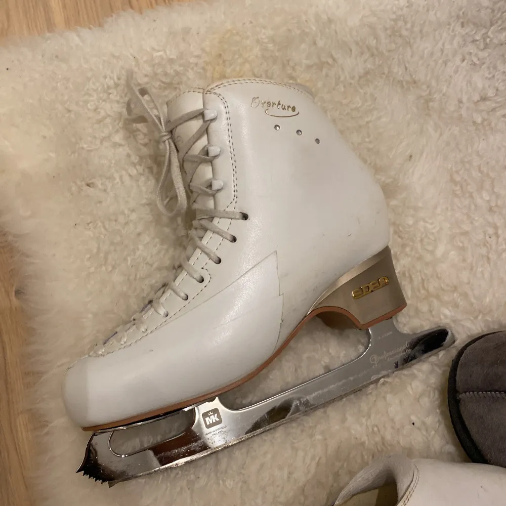 Säljer ett par eleganta vita konståkningsskridskor från Edea. De har en klassisk design med snörning och är utrustade med MK-blad för optimal prestanda på isen. Perfekta för både nybörjare och erfarna åkare.. Kengät.