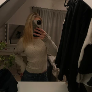 Beige stickad tröja - Säljer en mysig beige stickad tröja med långa ärmar. Perfekt för kyligare dagar och enkel att matcha med olika outfits. Tröjan har en klassisk design med ribbade detaljer vid ärmslut och nederkant.