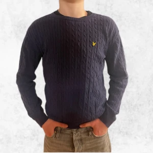 Marinblå kabelstickad tröja från Lyle & Scott - Säljer en riktigt snygg stickad tröja från Lyle & Scott med kabelstickat mönster. Tröjan har en gul logotyp på bröstet och långa ärmar. Perfekt för kyligare dagar! Den är storlek 14/15 år men sitter som en S. Vid frågor eller funderingar är det bara att höra av sig.