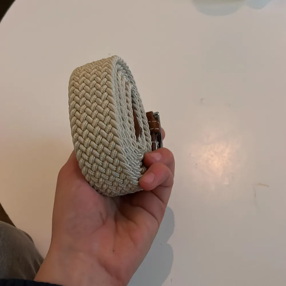 Säljer ett snyggt beige flätat bälte med ett stilrent silverfärgat spänne. Perfekt för att ge en extra touch till din outfit. Bältet har bruna detaljer vid spännet som ger en fin kontrast.100cm långt bälte. Muu.