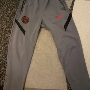 Nike x Psg tracksuit byxor - Hej säljer ett par Psg byxor från nike pågrund av att dom är för stora. Byxorna säljs så billigt pågrund av att det finns en liten defekt på bild 5 att kedjan är lite sönder men kan fixas. Storlek M men passar S pris kan diskuteras. Skriv vid minsta fundering och skriv innan köp⚡️🍾🍾