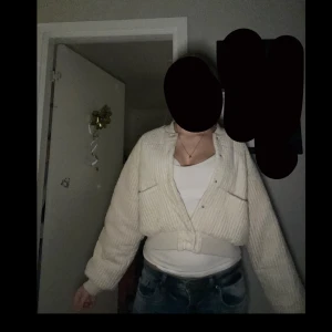 Beige ribbad croppad jacka - Säljer en beige ribbad croppad jacka med dragkedja framtill. Jackan har långa ärmar och en bekväm passform som passar perfekt för kyligare dagar. Perfekt för att lägga till en stilren touch till din outfit.