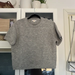 Grå stickad tröja från Gina Tricot - Säljer en mysig grå stickad tröja från Gina Tricot. Tröjan har korta ärmar och en rund halsringning, perfekt för lager på lager under kyligare dagar. Enkel och stilren design som passar till det mesta. Perfekt för höst och vår! Kom privat för fler bilder💖