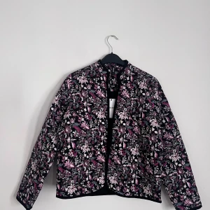 Jacka  - Supersöt och lätt jacka med blommönster. Jackan stängs med knappar.