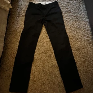 Svarta byxor från Dickies - Säljer ett par svarta slim fit byxor från Dickies. De är i bra skick och perfekta för både vardag och fest. Byxorna har en klassisk stil och är gjorda i ett slitstarkt material. Kan Mötas upp i Värmland
