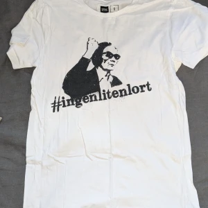 Vit t-shirt med tryck från Dedicated - Säljer en vit t-shirt som köptes på Astrid Lindgrens värld med ett coolt tryck. T-shirten är gjord av 100% ekologisk och Fairtrade-certifierad bomull.