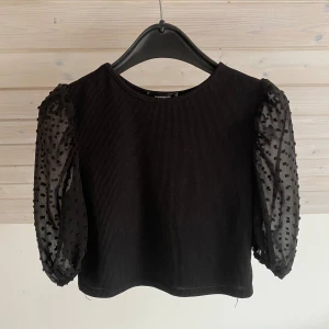 Svart topp  - Svart topp med lite puffiga genomskinliga ärmar. 