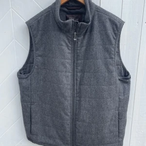 Oscar Jacobson väst - Säljer en stilren och varm grå väst från Oscar Jacobson. Den är quiltad och har en dragkedja framtill. Perfekt för höst och vinter, och den är i nyskick. Västen har en klassisk design som passar till många olika outfits.
