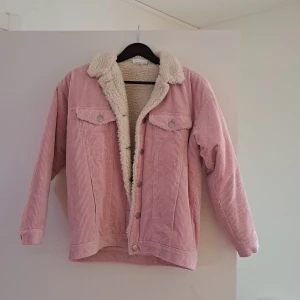 Rosa manchesterjacka med teddyfoder - Säljer en superfin rosa manchesterjacka med mysigt teddyfoder. Jackan har knappar framtill och två bröstfickor med lock. Perfekt för höst och vår när du vill vara både varm och stilren. Lite smudsig men det går att tvätta bort den. Passar Xs- S & M