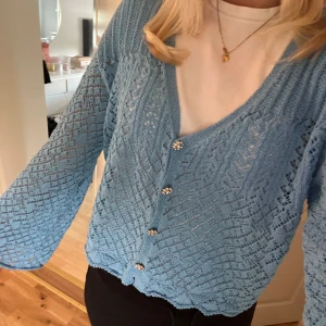 Blå stickad kofta med blommiga knappar - Säljer en superfin blå stickad kofta med unika blommiga knappar. Den har en luftig och bekväm passform med långa ärmar.  🌸