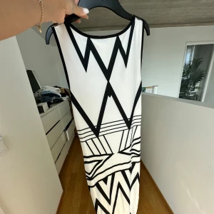 Klänning  - Letar du efter det ultimata statement-plagget för ditt nästa evenemang? Sök inte längre! Vår ärmlösa, rygglösa festklänning utstrålar elegans och sofistikering. Med sin eleganta design och smickrande silhuett är denna klänning perfekt för att göra en