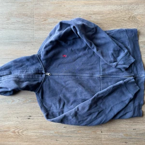 Mörkblå hoodie från Polo Ralph Lauren - Säljer en snygg och bekväm mörkblå hoodie från Polo Ralph Lauren. Den har en dragkedja framtill och en liten röd logga på bröstet. Perfekt för en avslappnad stil och passar bra till både höst och vinter. Den är i bra skick och redo för nya äventyr!