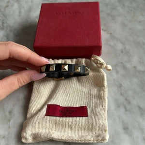 Svart valentino armband - Svart Valentino armband med guldiga studs. Bra skick men använt, normalt slitage på kanten (se bild). Dustbag, låda och studs ingår.