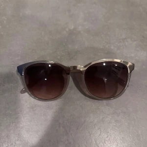 Solglasögon med brun toning - Snygga solglasögon med en stilren design. De har en brun toning på glasen och en transparent ram som ger en modern look. Perfekta för soliga dagar och passar till de flesta outfits.