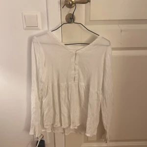 Vit blus från Angelology - Säljer en söt vit blus från Angelology i storlek S. Blusen har långa ärmar och en knappdetalj framtill. Perfekt för en stilren och avslappnad look. 💗