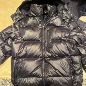 Marinblå  pufferjacka från Ralph Lauren - Snygg marinblå vinterjacka  från Ralph Lauren. Eftertraktad och slutsåld i affärerna! Superfint skick!